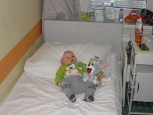 na szpitalnym łóżku małe dziecko i maskotka