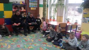 w szkolnej klasie dzieci siedzą na podłodze, policjanci na krzesełkach czytają ksiązki