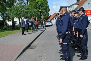 policjanci stoją w pododdziale na ulicy w mikołajkach przy pomniku