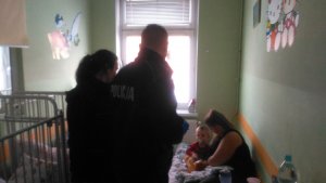 sala szpitalna, policjant i policjantka, matka z dzieckiem na łóżku