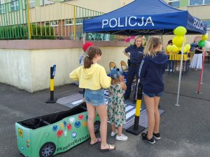 szkolny plac dzieci i policyjne stanowisku, policjantka i rozłożony autochodzik