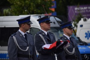 poczet flagowy trzech policjantów jeden trzyma złożona flagę polski