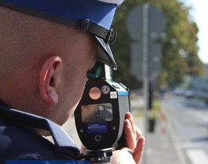 policjant trzymający w ręku urządzenie do pomiaru prędkości