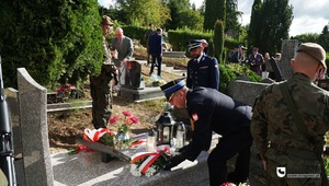 Komendant Powiatowy Policji w Mrągowie i Komendant Straży Pożarnej w Mrągowie kładą kwiaty na grobie