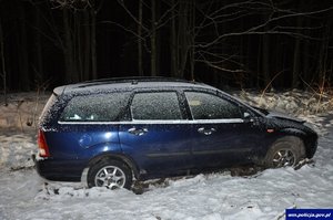 samochód osobowy koloru granatowego stojący w śniegu na leśnej drodze
