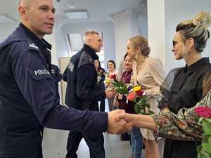 na sali odpraw stoją kobiety a 2 policjantów- komendanci wręczają im kwiaty