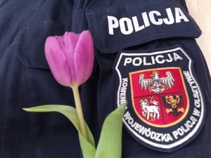 tulipan na tle emblematu Komendy Wojewódzkiej Policji w Olsztynie