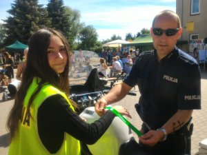 policjant zakłada na rękę dziewczyny odblask